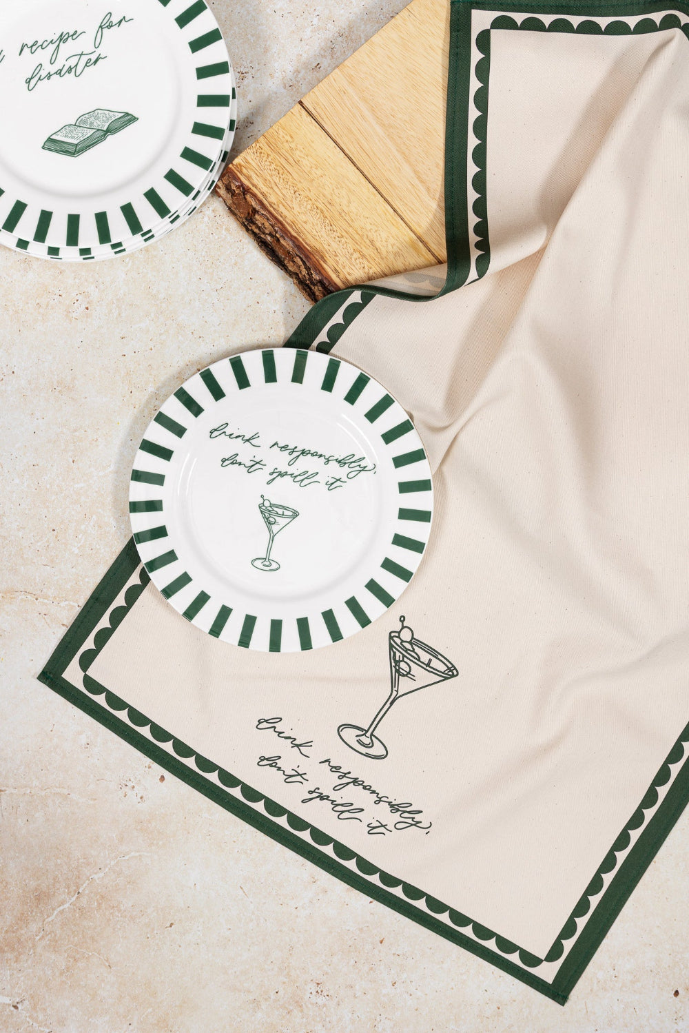 Two round bone chine plates with green and white designs on a matching tea towel design
