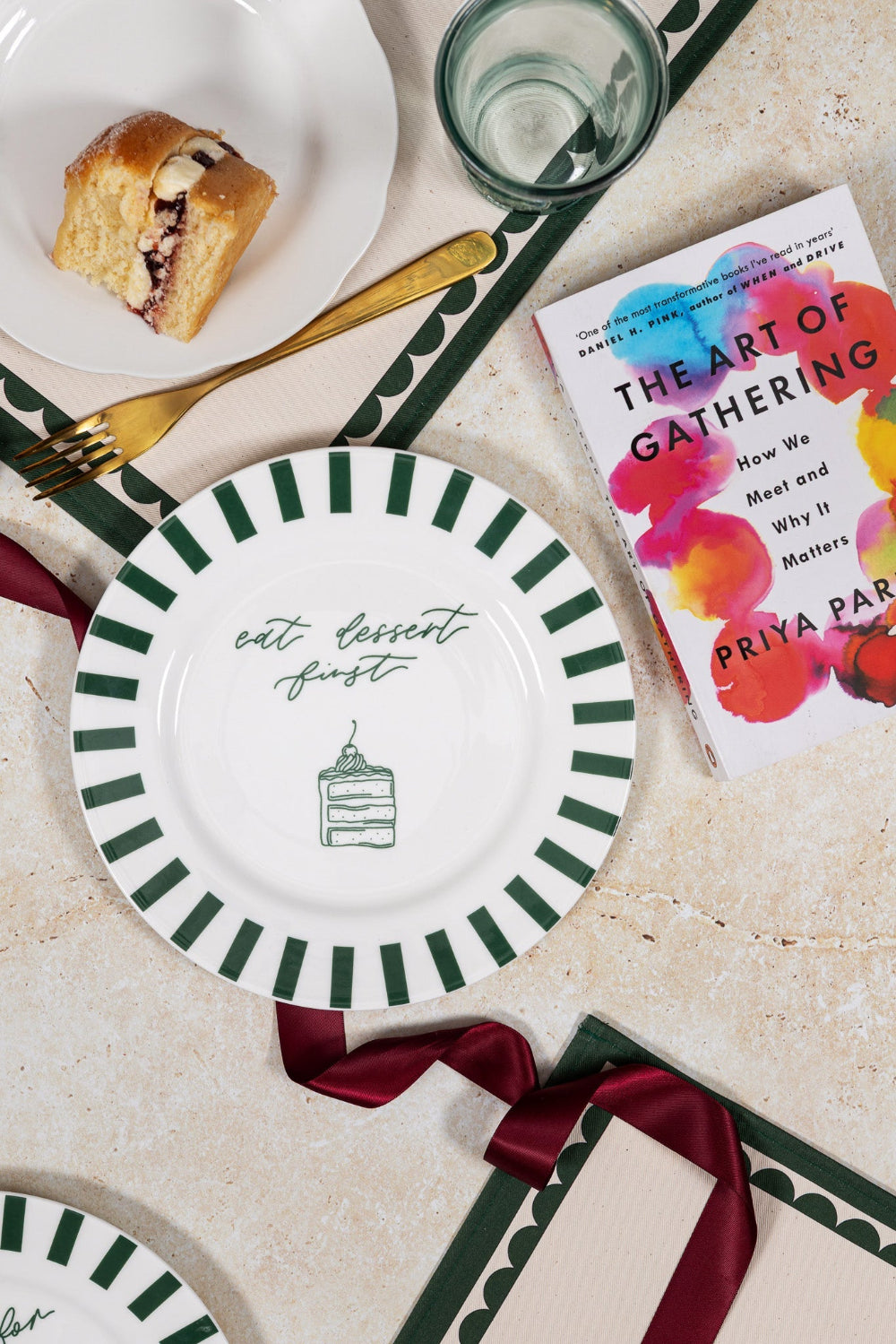 Table setting with decorative plates, a book titled 'The Art of Gathering', and a pastry.