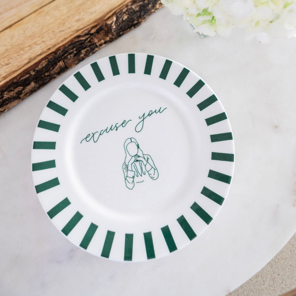 White plate with green stripes and 'excuse you' text on a light background