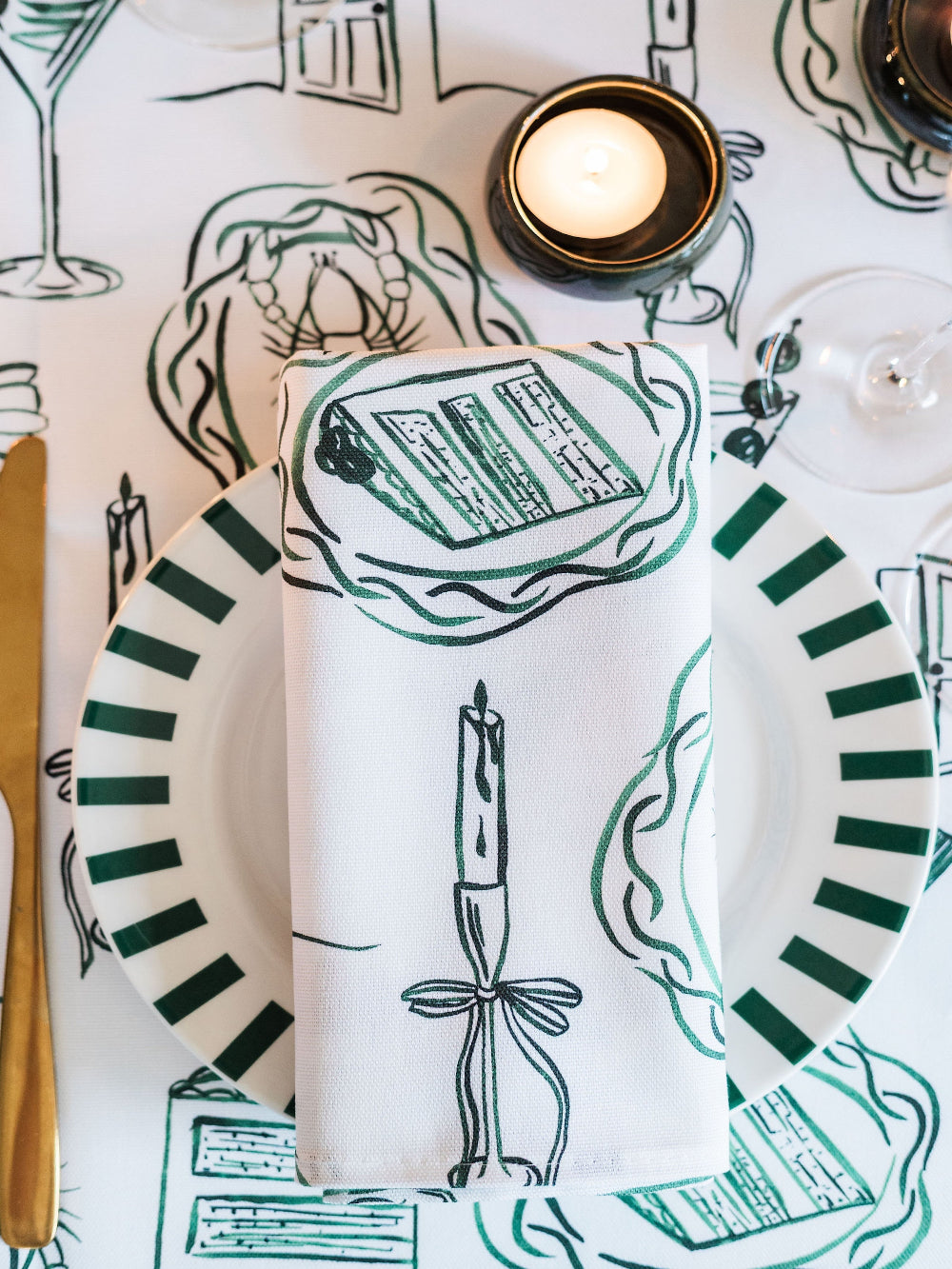 Placemat with green and white design featuring a candle and text, on a table setting.