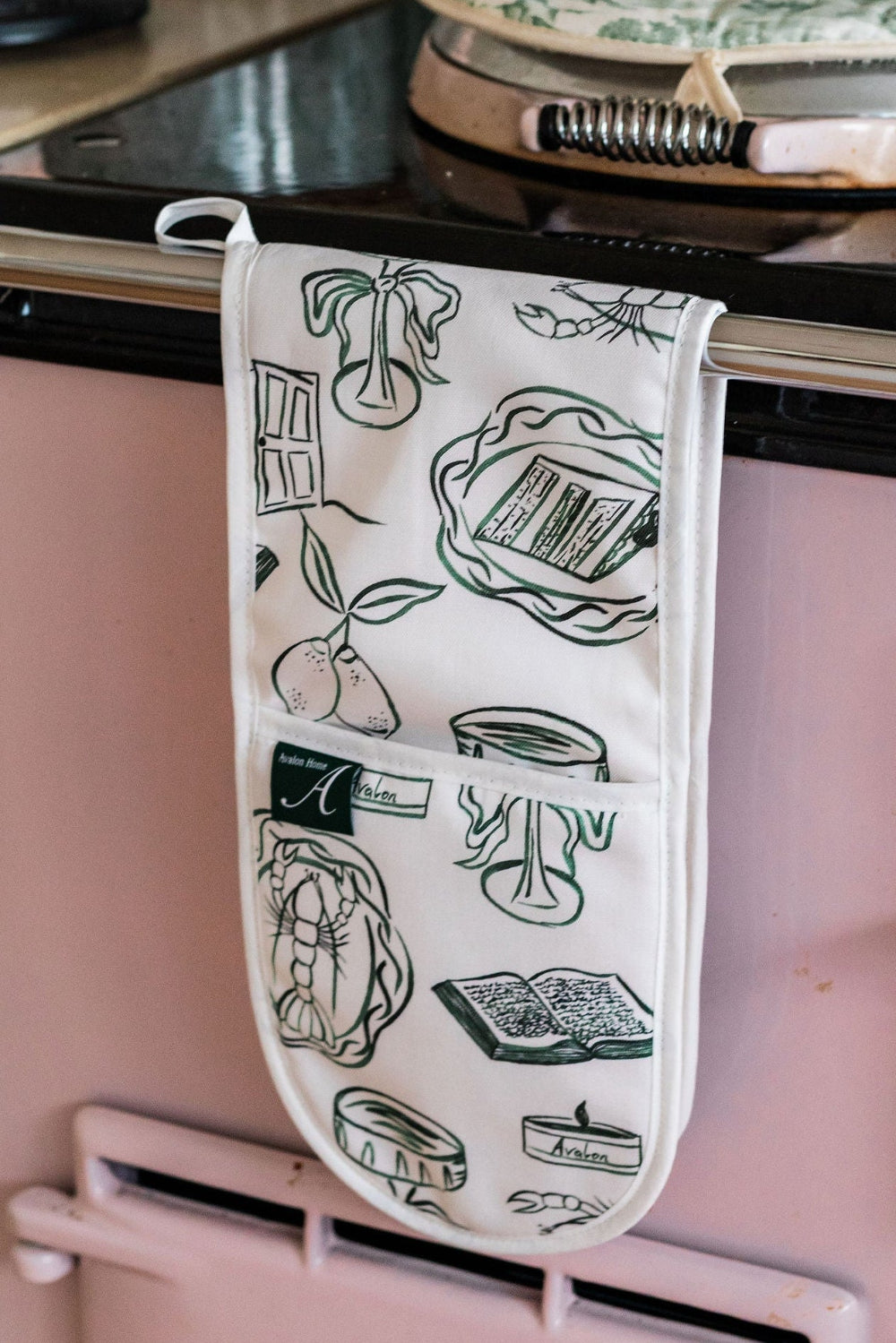 Oven mitt with green illustrations hanging on a stove handle
