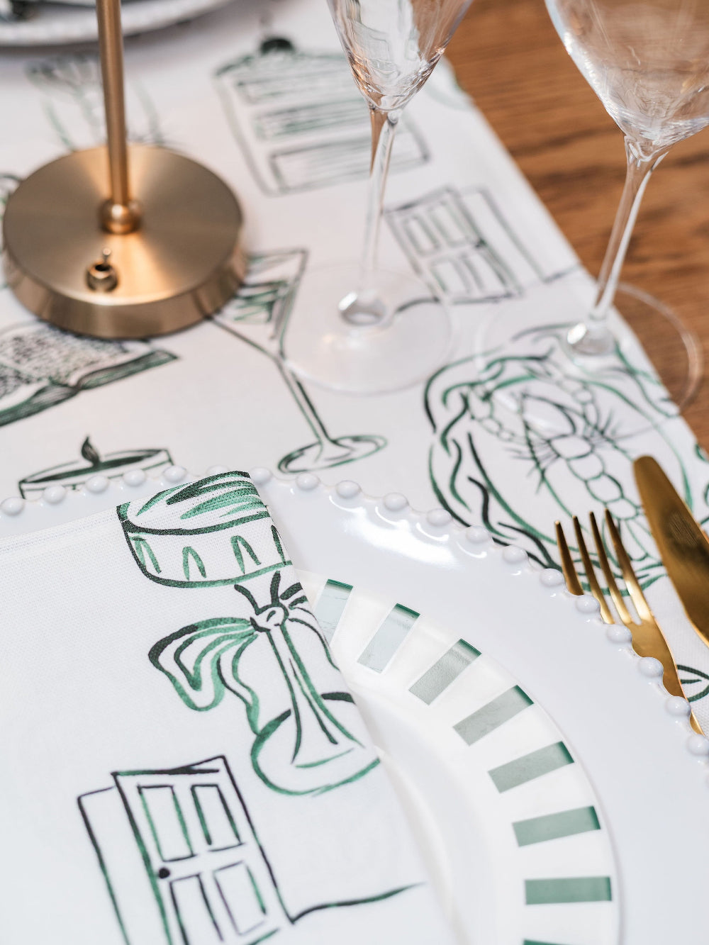 Table setting with decorative runner featuring artistic designs and gold cutlery.