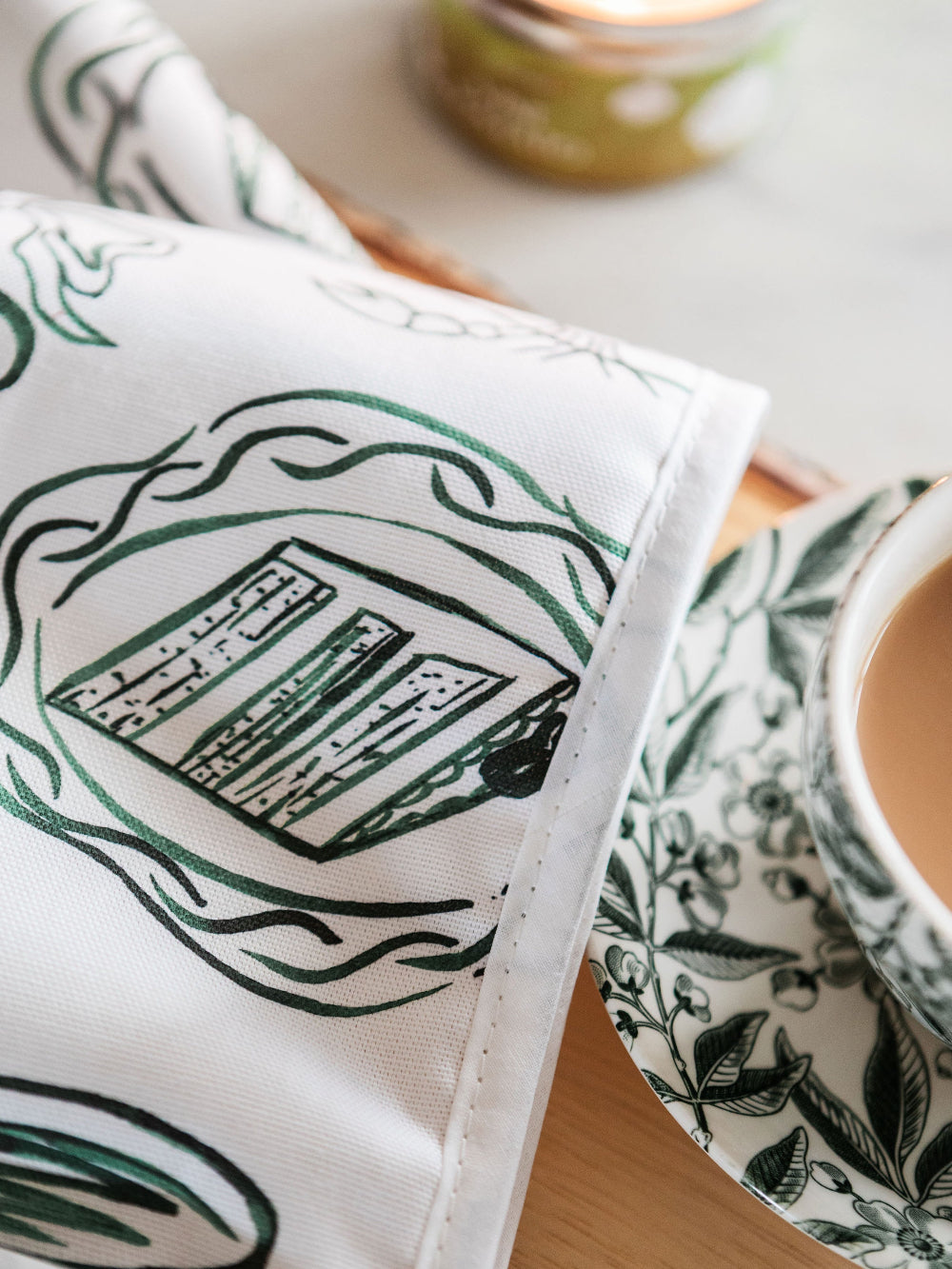 Close-up of a Oven Mitts with green floral patterns, placed on a wooden surface.