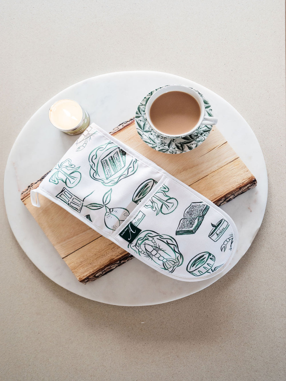 Wooden cutting board with a Oven Mitt and cup and saucer on a white plate