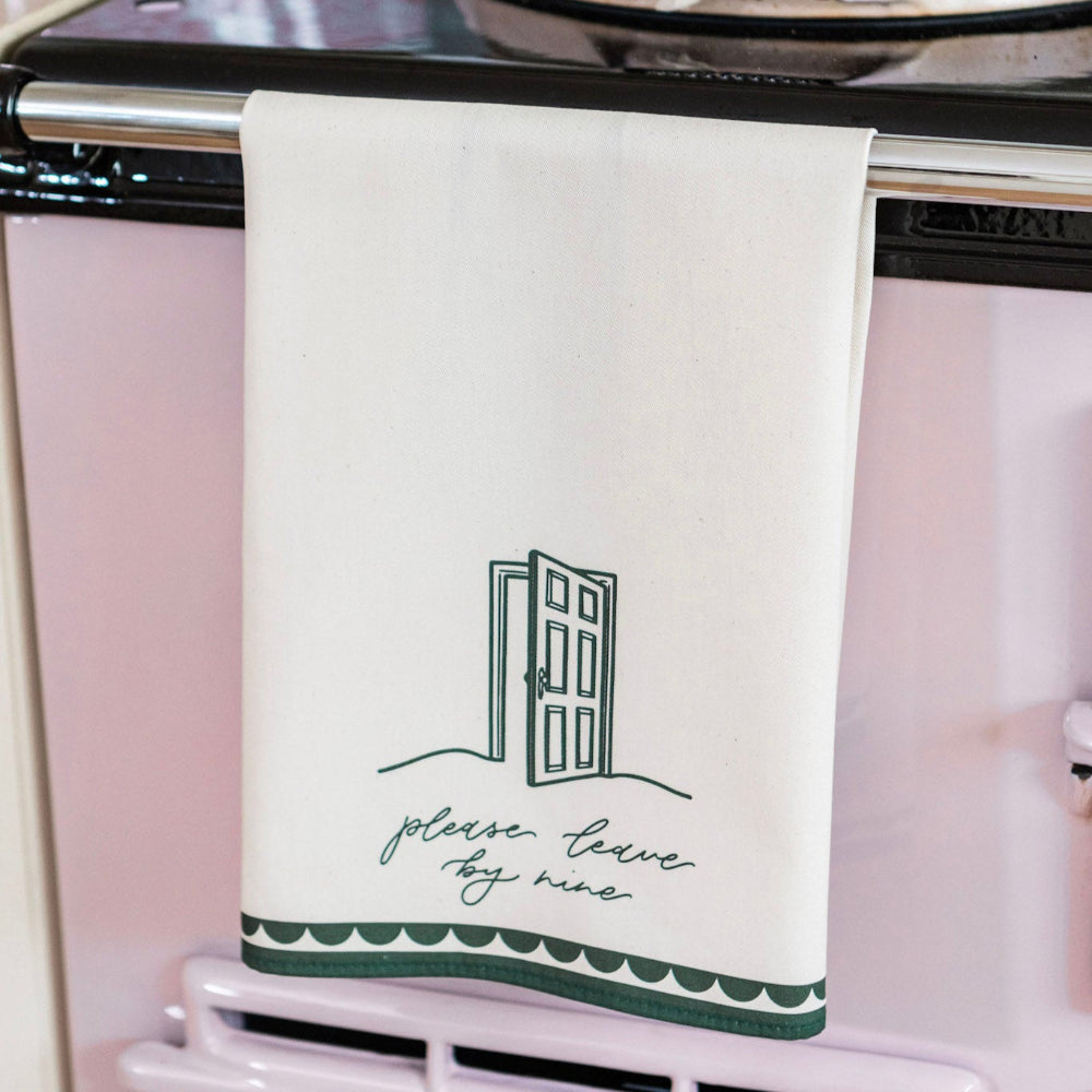 Tea Towel with 'please leave by nine' text hanging on a pink stove