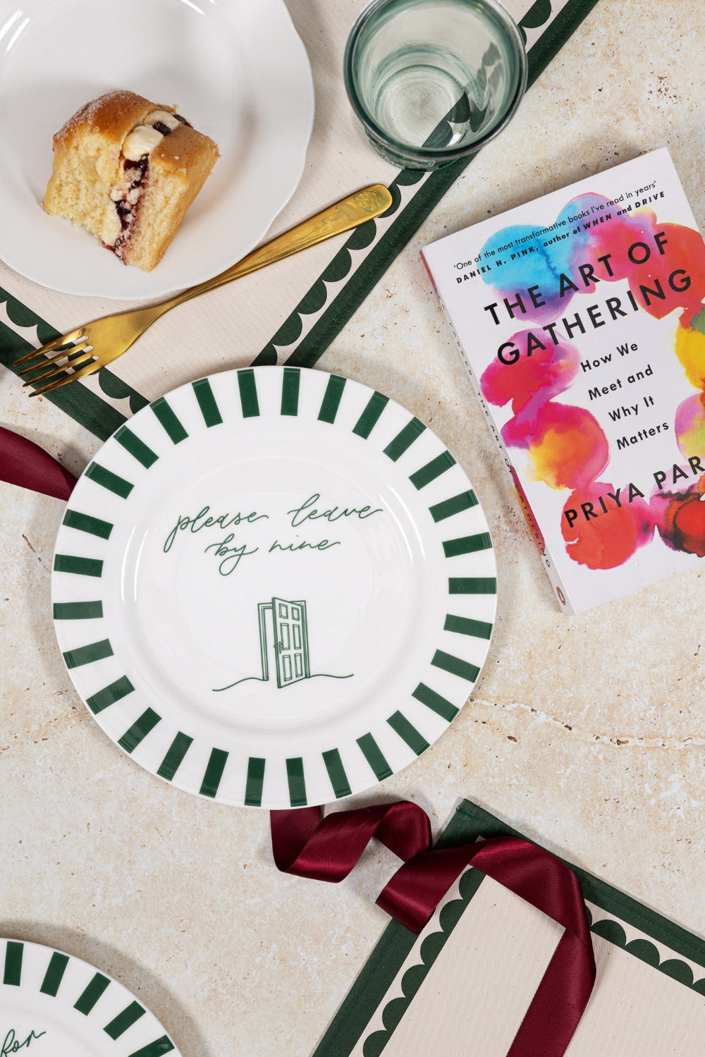 Table setting with plates, a glass, a book titled 'The Art of Gathering', and a piece of bread.