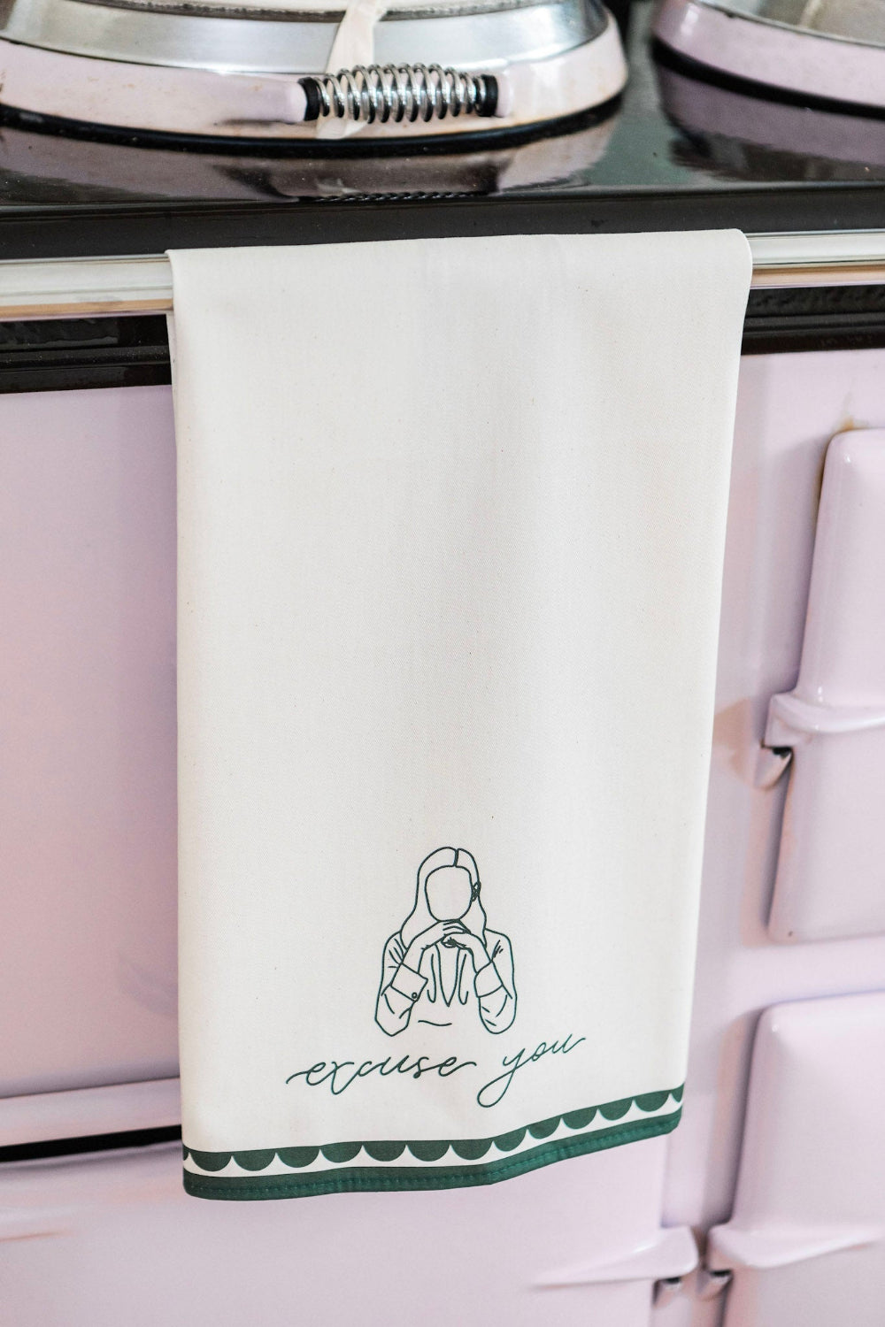Kitchen towel with a design and 'excuse you' text hanging on a stove