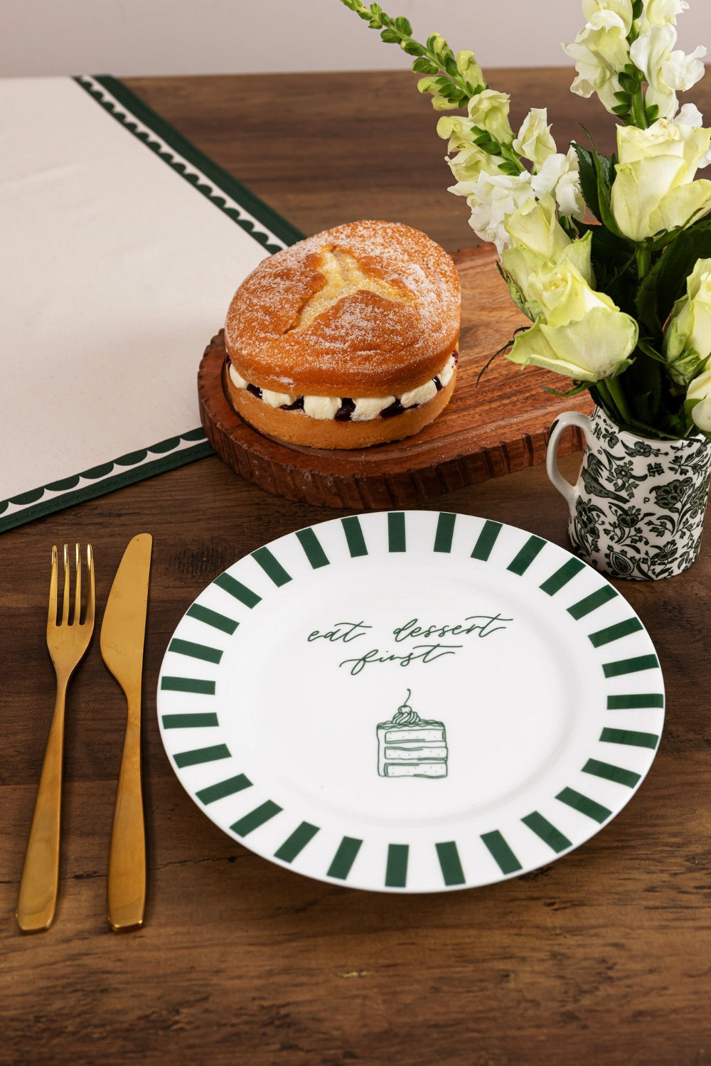 Dessert plate with decorative text, pastry, and flowers on a wooden table.