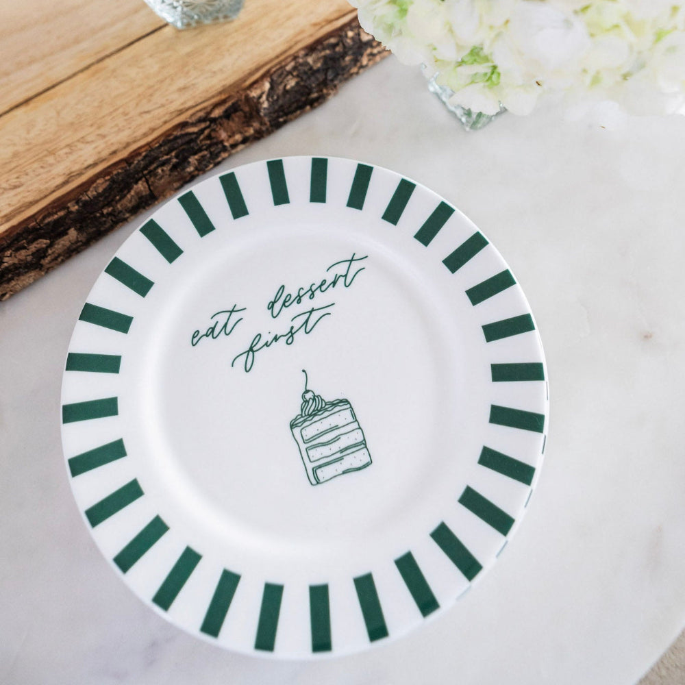 White plate with green striped rim and text 'eat dessert first' on a light background