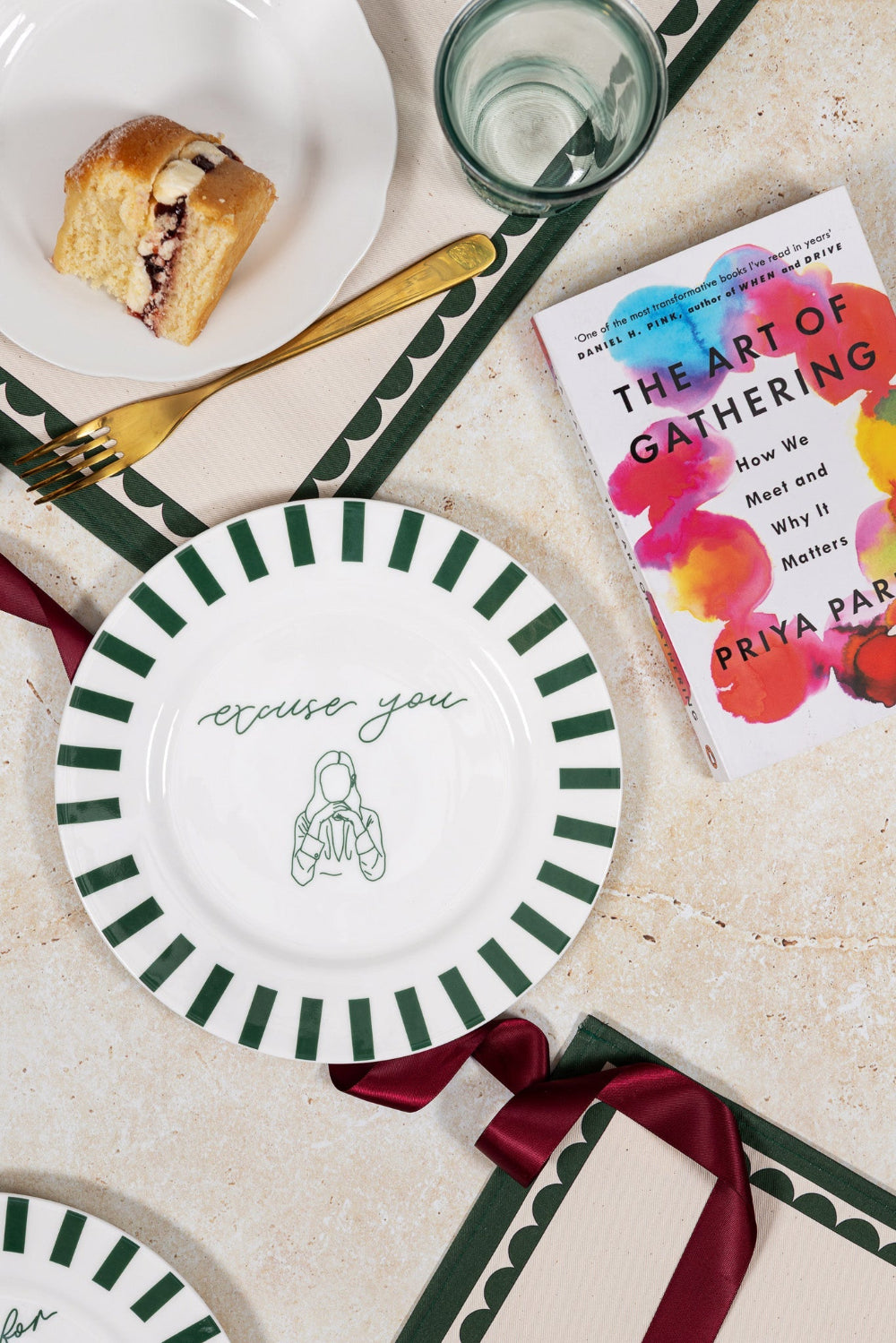 Table setting with plates, a book titled 'The Art of Gathering', and a pastry.