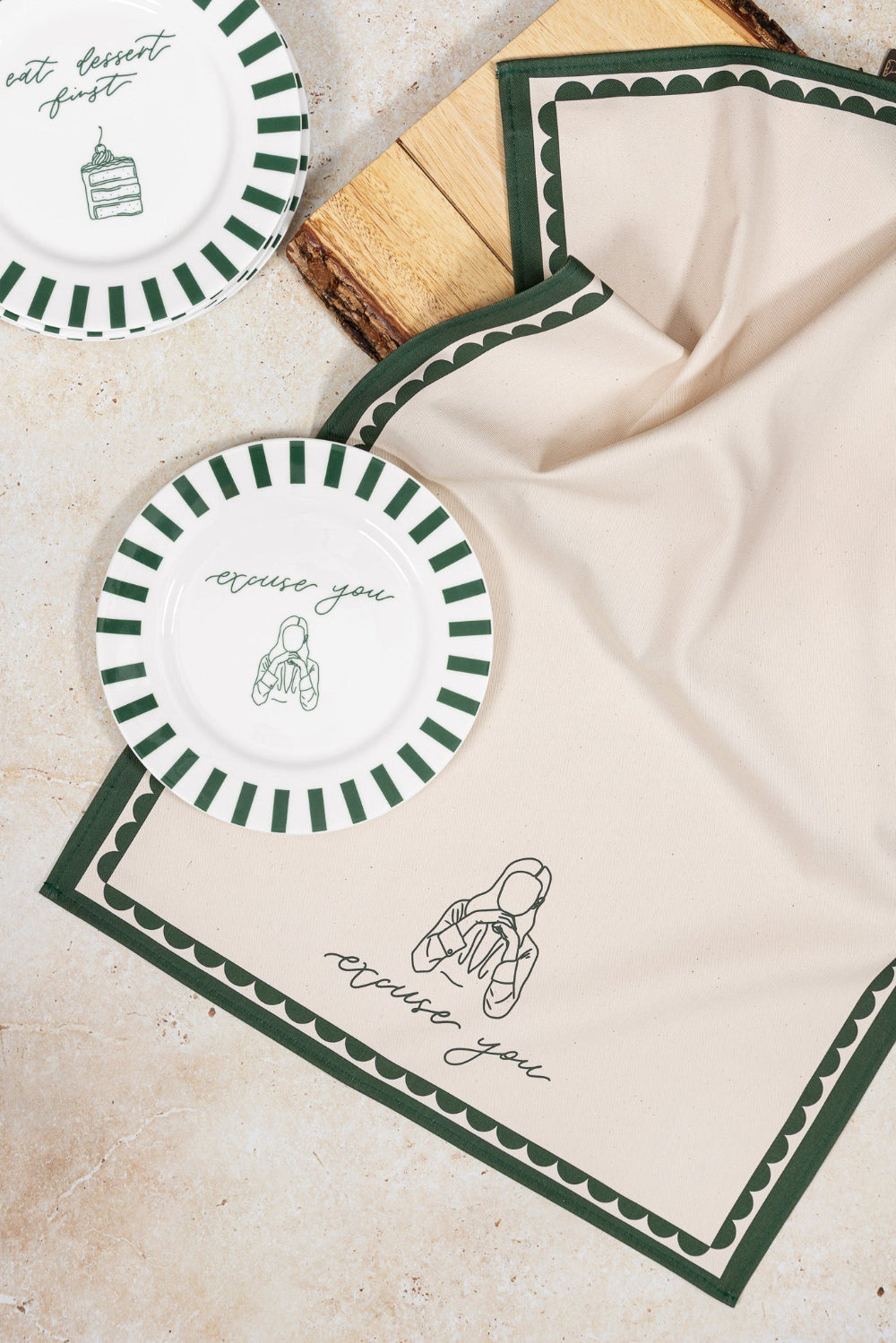 White plate with green 'excuse you' text and borders on a beige matching tea towel