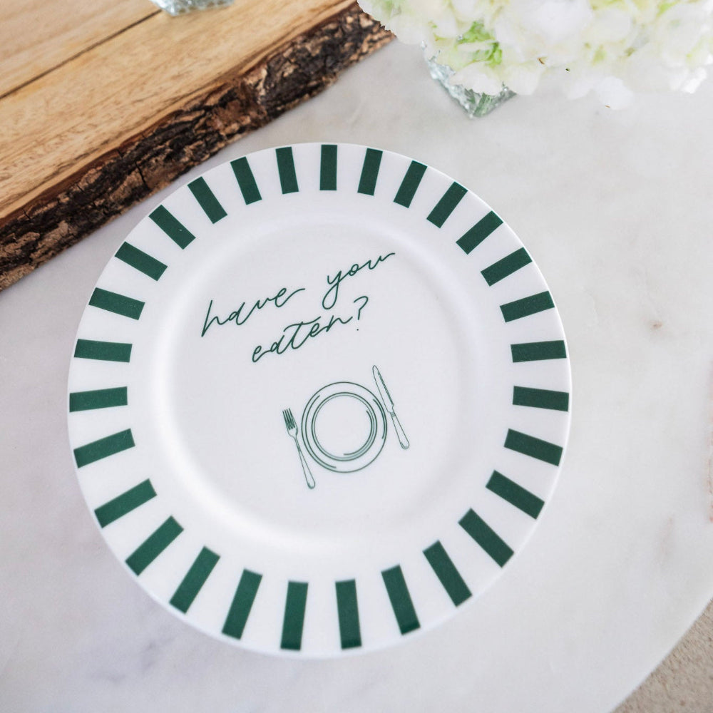 White plate with green stripes and 'have you eaten' text on a light surface