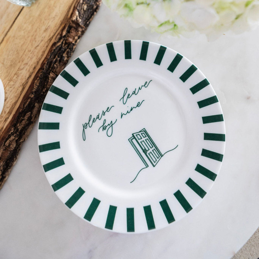 White plate with green stripes and 'please leave by 9' text on a marble work surface