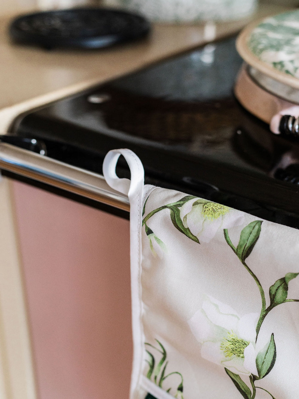 Floral-patterned pot holder hanging on a stove handle