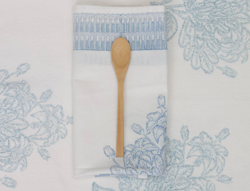 Napkin with blue floral pattern and wooden spoon on a matching background