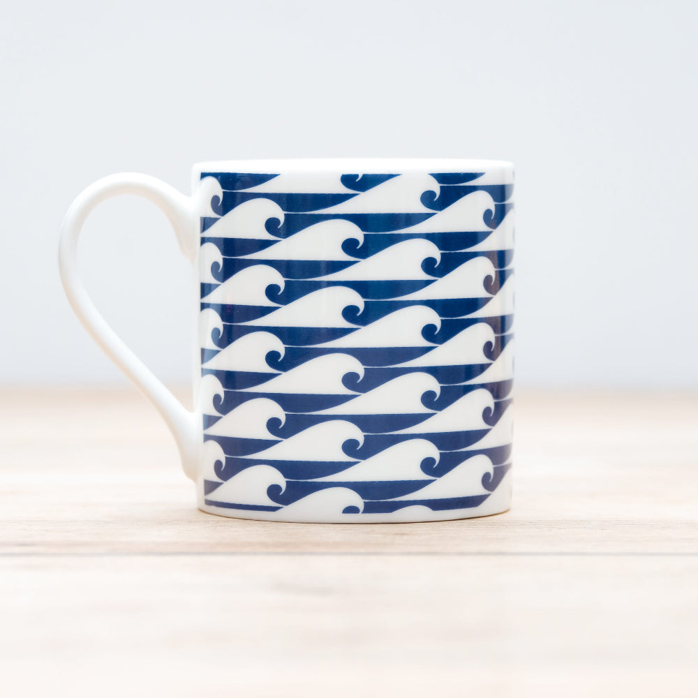 White mug with blue wave pattern on a light wooden surface