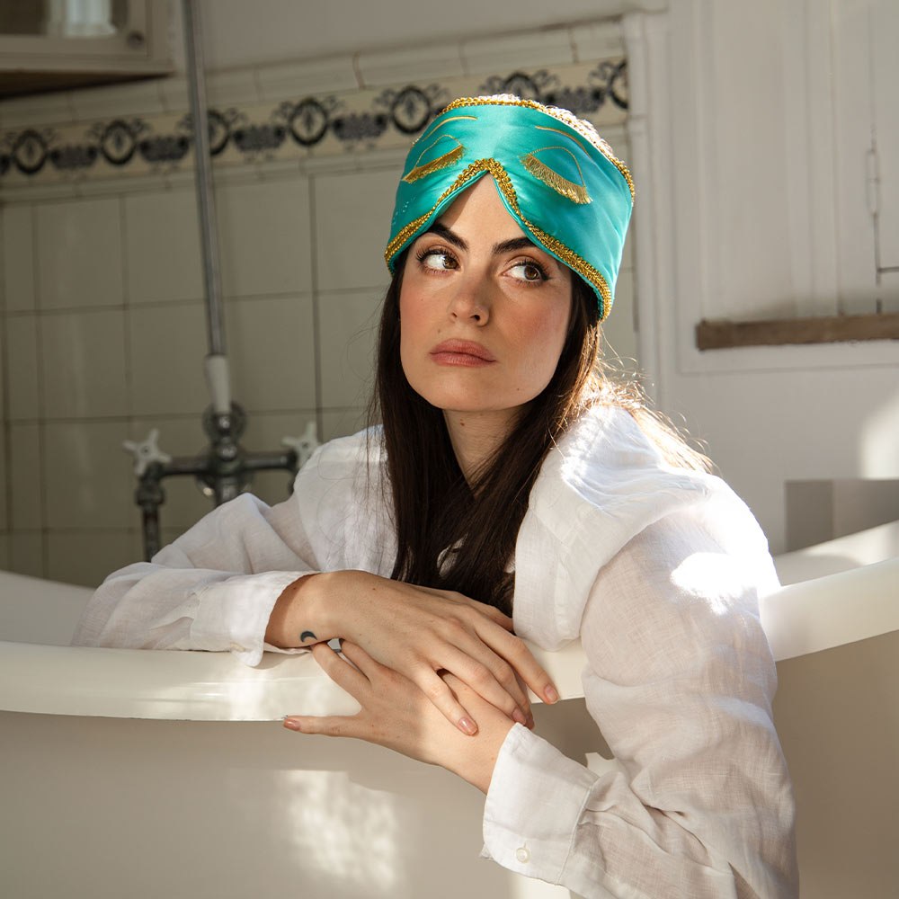 Woman in white shirt and a breakfast at Tiffany's inspired sleep eye mask in a bathtub in a vintage style bathroom