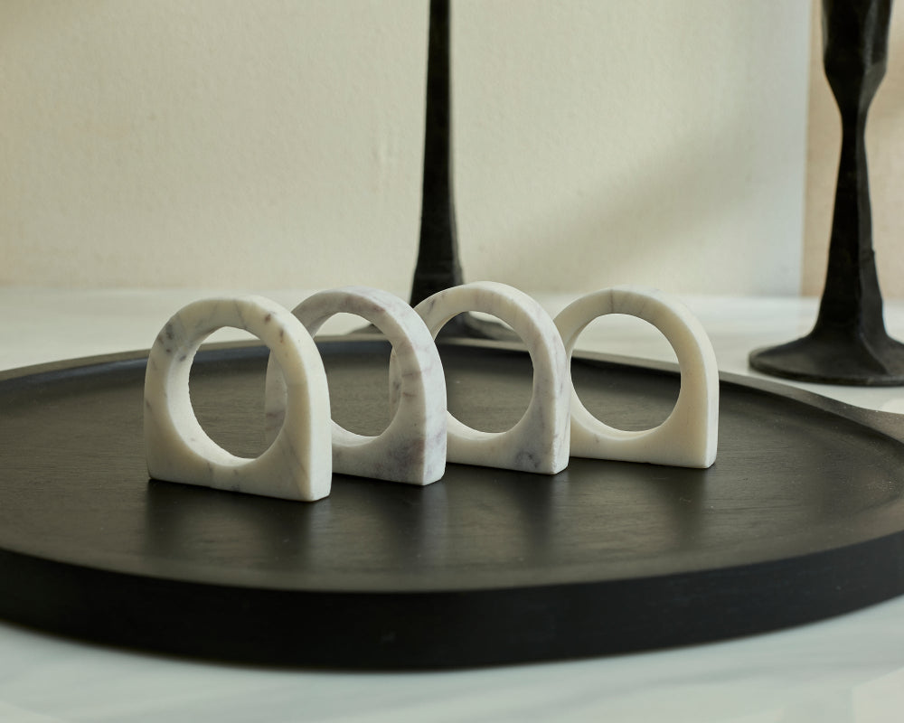 Set of four white marble ring-shaped objects on a dark surface with a neutral background