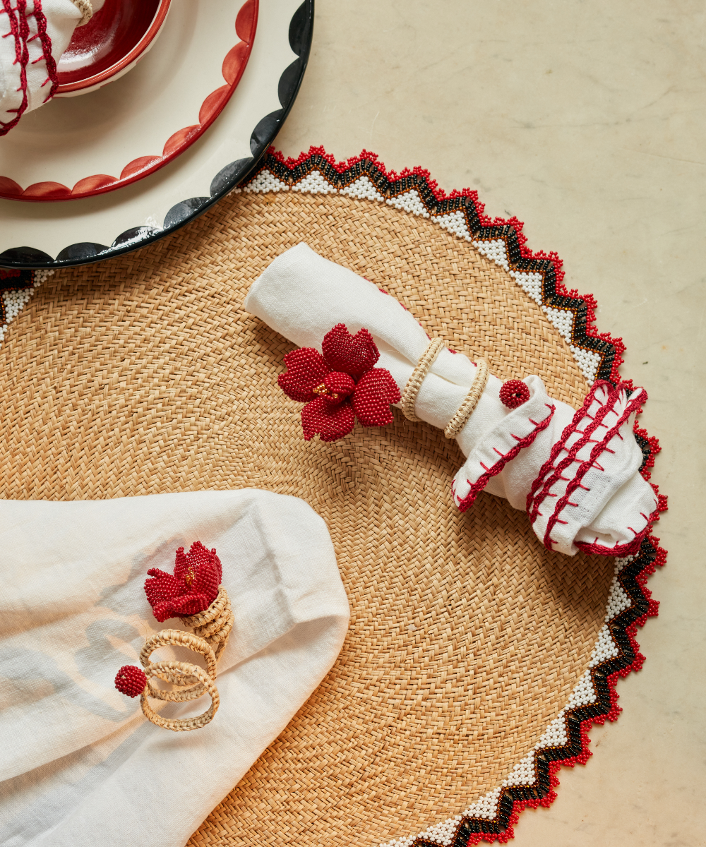 Decorative napkin rings with red flowers on a woven placemat.