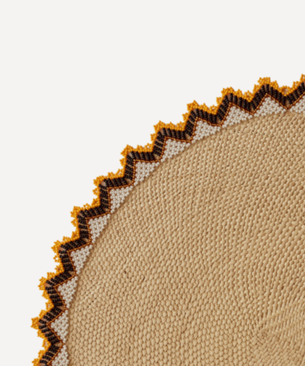 Close-up of beige fabric with brown zigzag trim on a light grey background