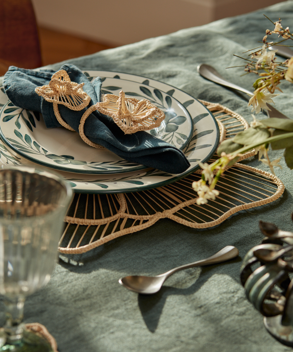 Casalatina Cayena Napkin ring wrapped around blue linen napkin on green and white ceramic plates on a dining table setting
