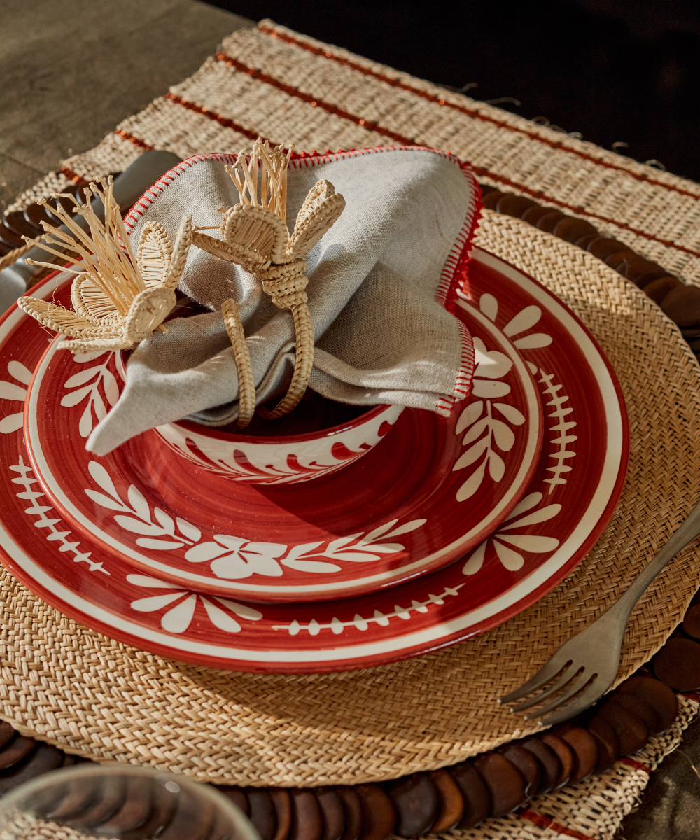 Decorative place setting with red and white plates, silverware, and a woven placemat.