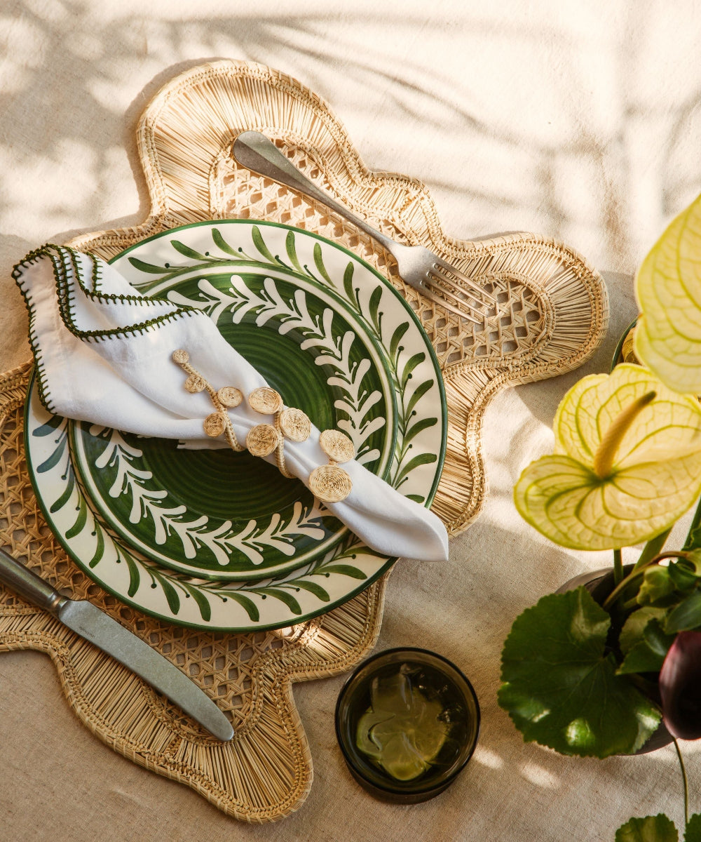Decorative table setting with green and white plates, napkins, and a woven placemat.