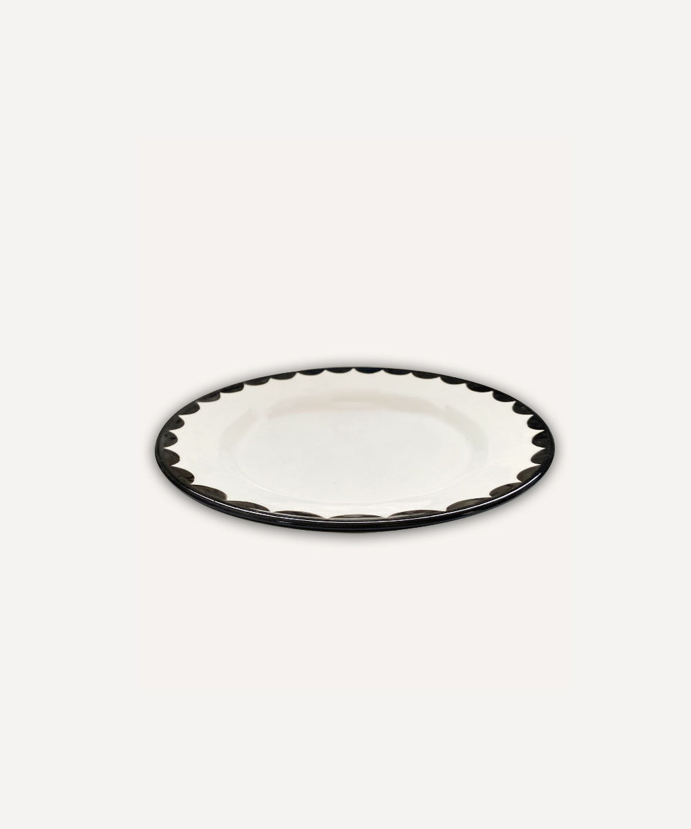 White ceramic side plate with jet black scalloped edge on a white background