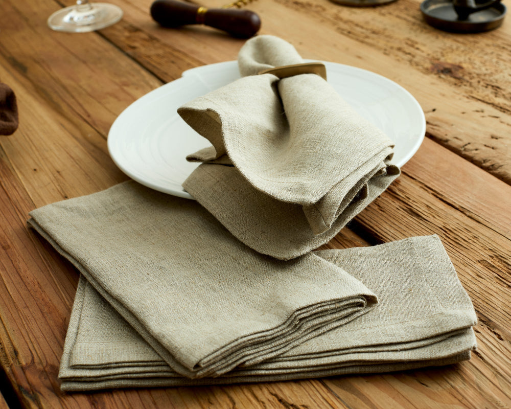 Folded beige napkins on a white plate on a wooden table