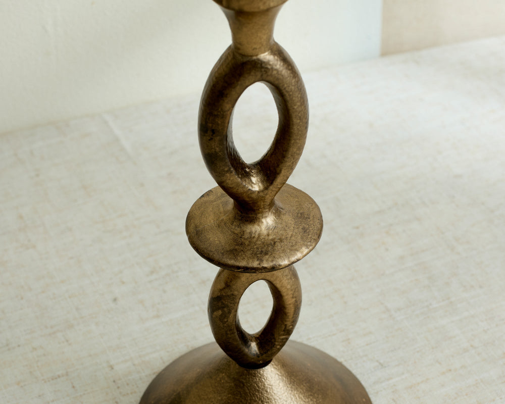 Bronze candle holder with circular design on a textured surface