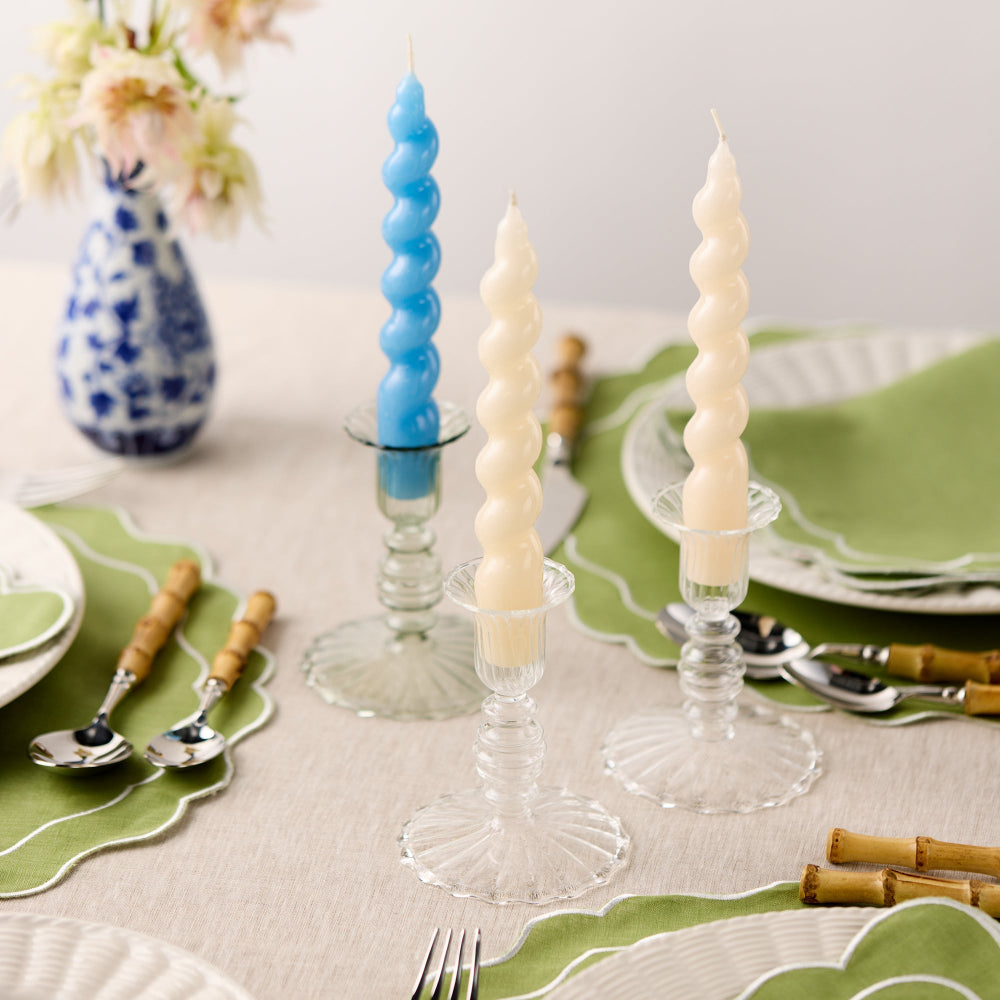 Decorative spiral candles on a table setting with green placemats and floral arrangement.
