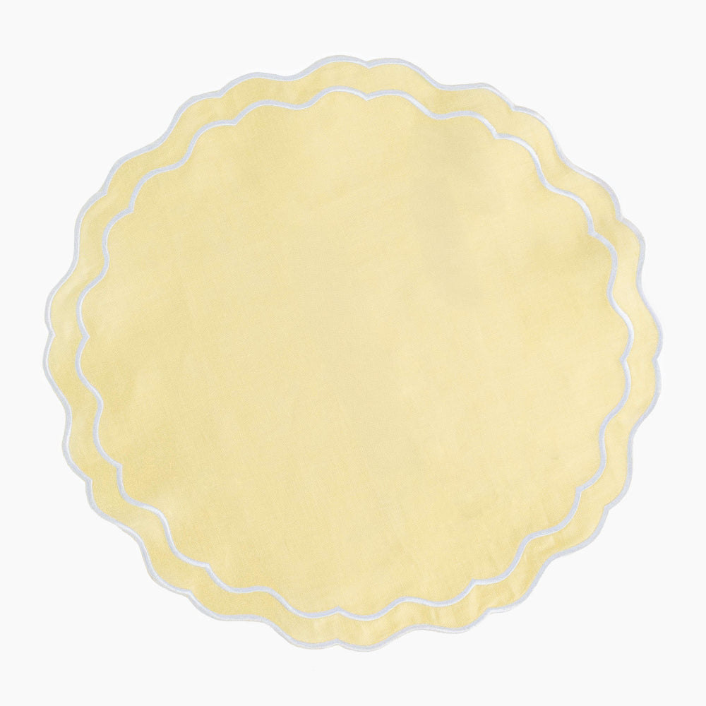 Round scalloped edge placemat in buttermilk yellow on a white background