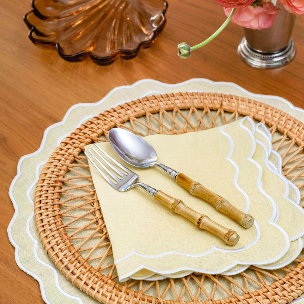 Wicker placemat with Buttermilk yellow napkin and placemat with cutlery on a wooden table