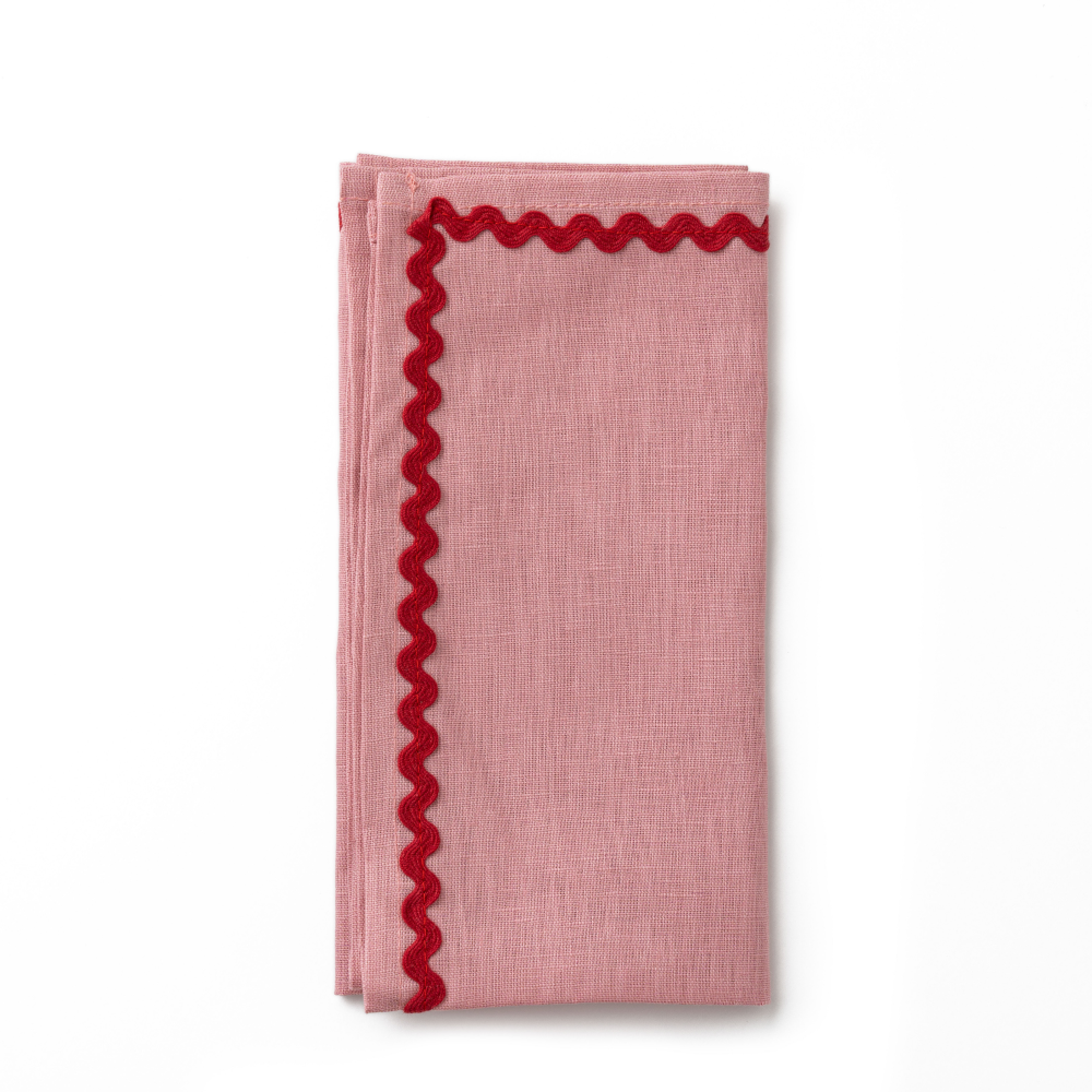 Pink napkin with red scalloped edge on a white background