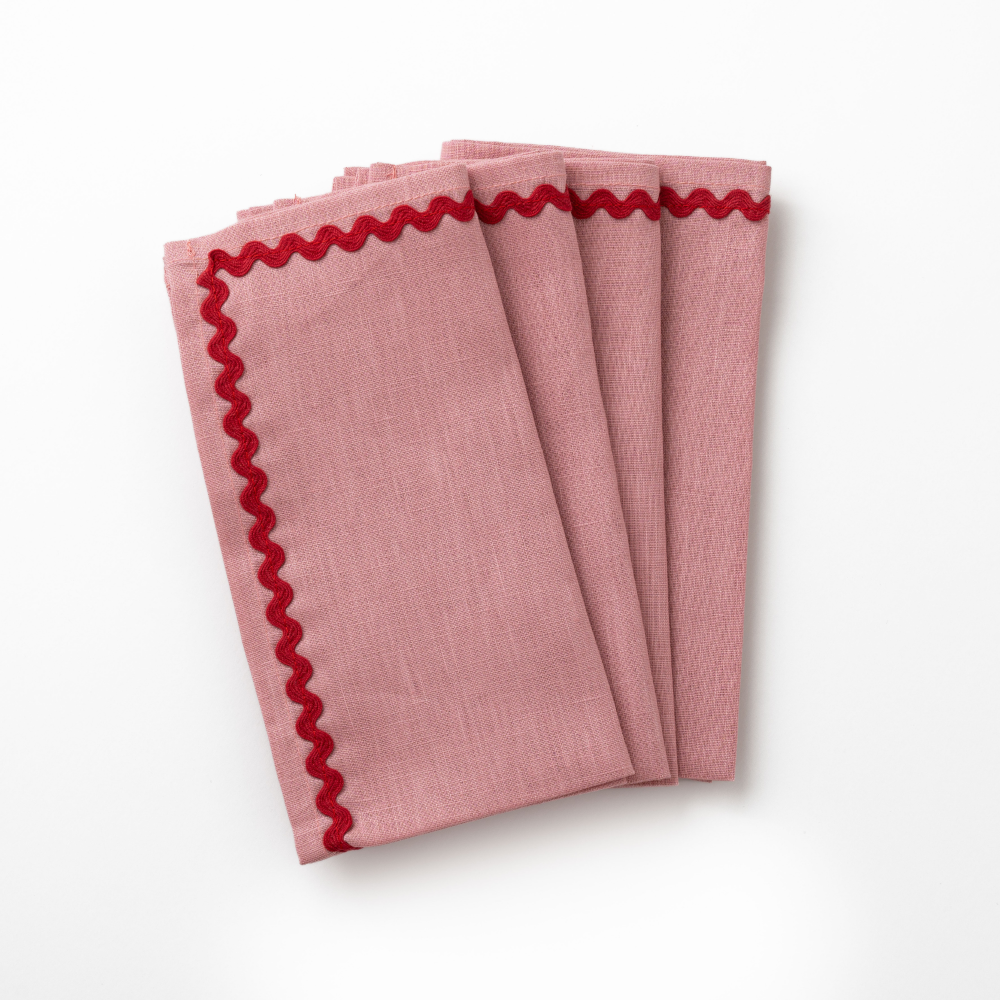 Four pink napkins with red scalloped edges waves on a white background