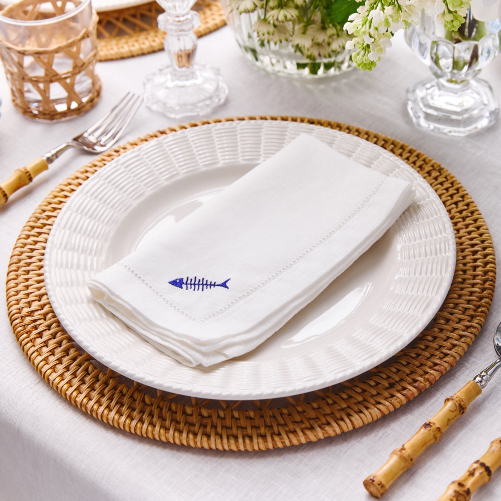 Elegant table setting with white plates, linen napkins, and decorative elements on a white tablecloth.