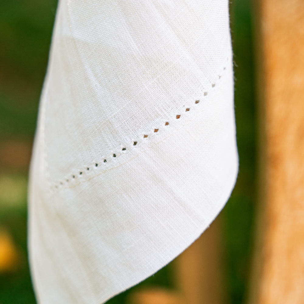Close-up of a white tablecloth with embroidery against a blurred natural background