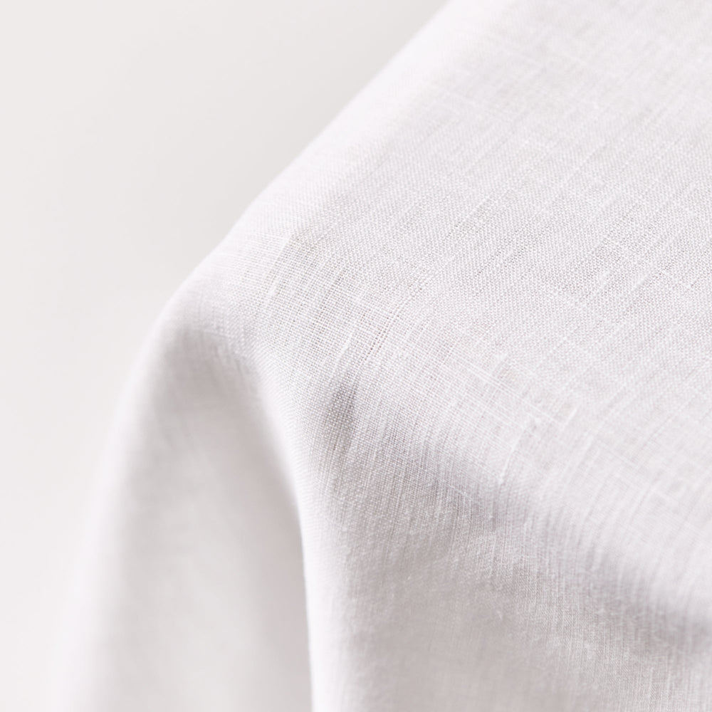 Close-up of white hemstitched tablecloth texture on a light grey background