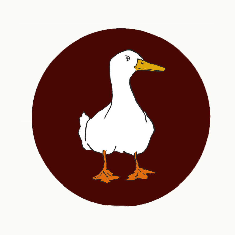 White duck with orange feet and beak on a brown circle placemat on a white background
