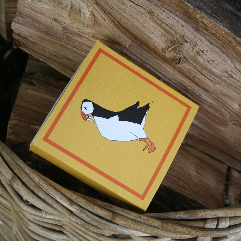 Small yellow box with a puffin illustration on a wooden surface
