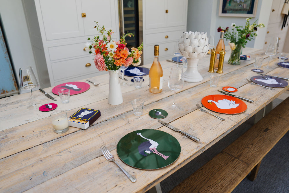 Wooden table set with colourful coasters, bottles, and decorative items.