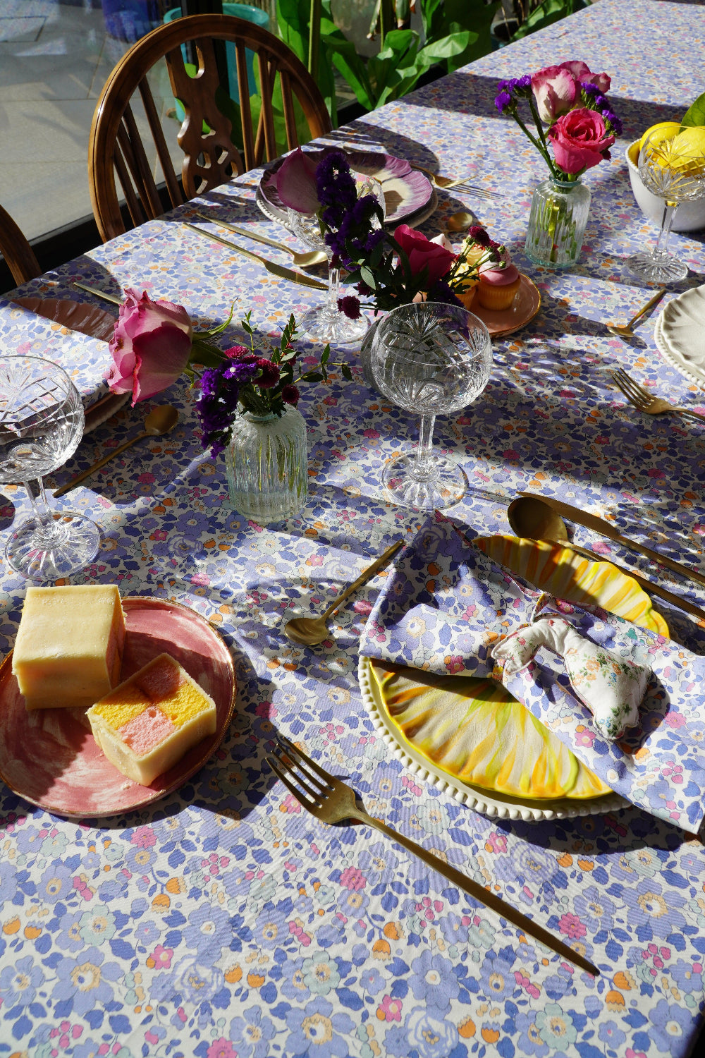Dining table set with floral tablecloth, plates, cutlery, and decorative items.