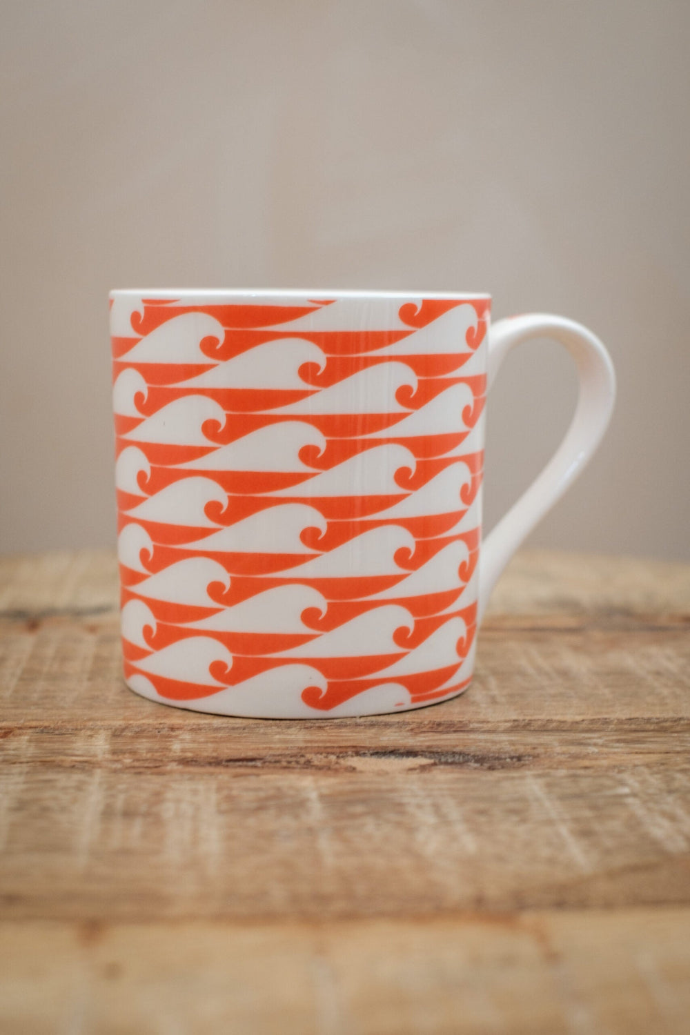White mug with orange wave pattern on a wooden surface
