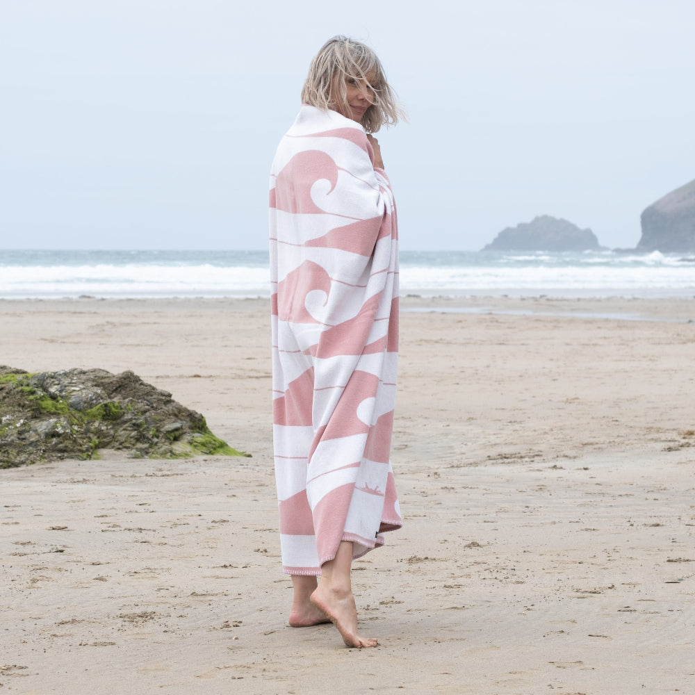 Woman wrapped in a pink and white patterned towel on a beach