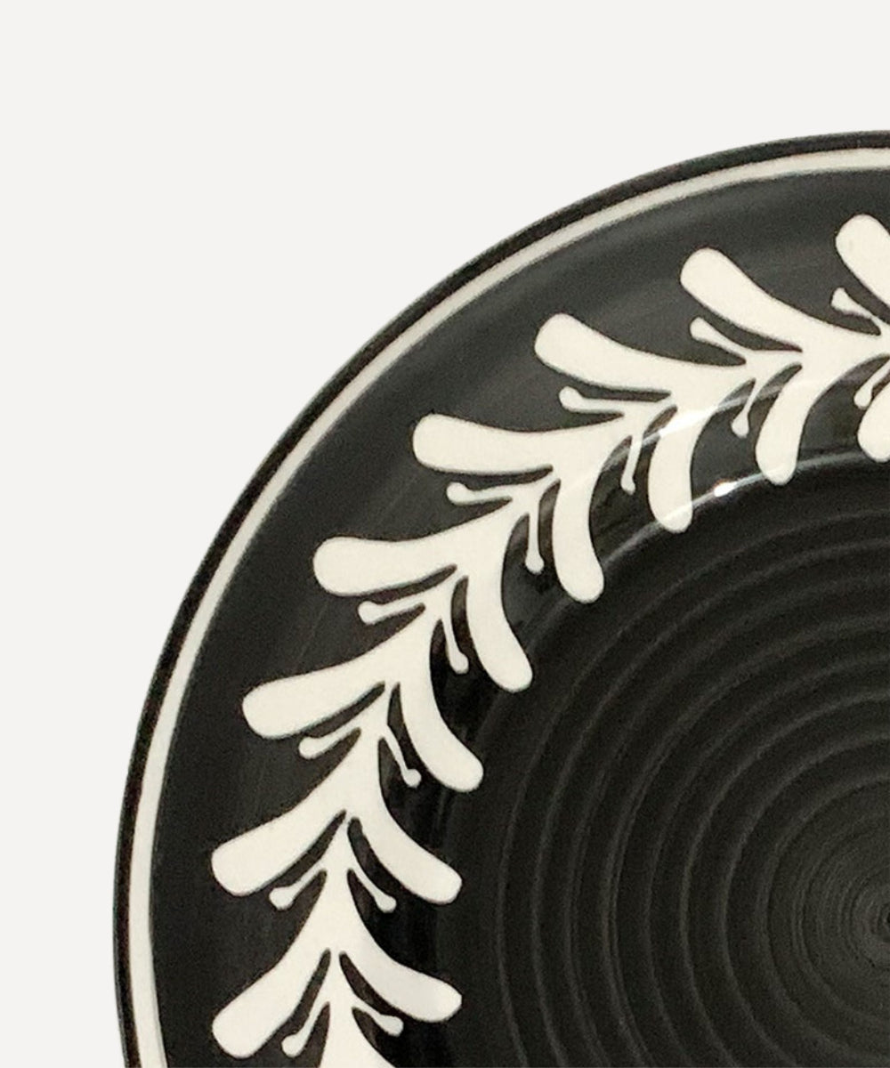 Black plate with white leaf pattern on a white background