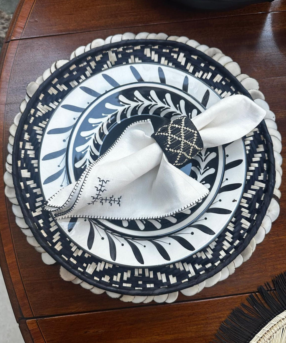 Decorative plate with a white napkin and black and white pattern on a wooden surface