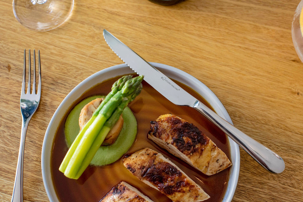 Studio William Cutlery resting on a plate with chicken asparagus and gravy