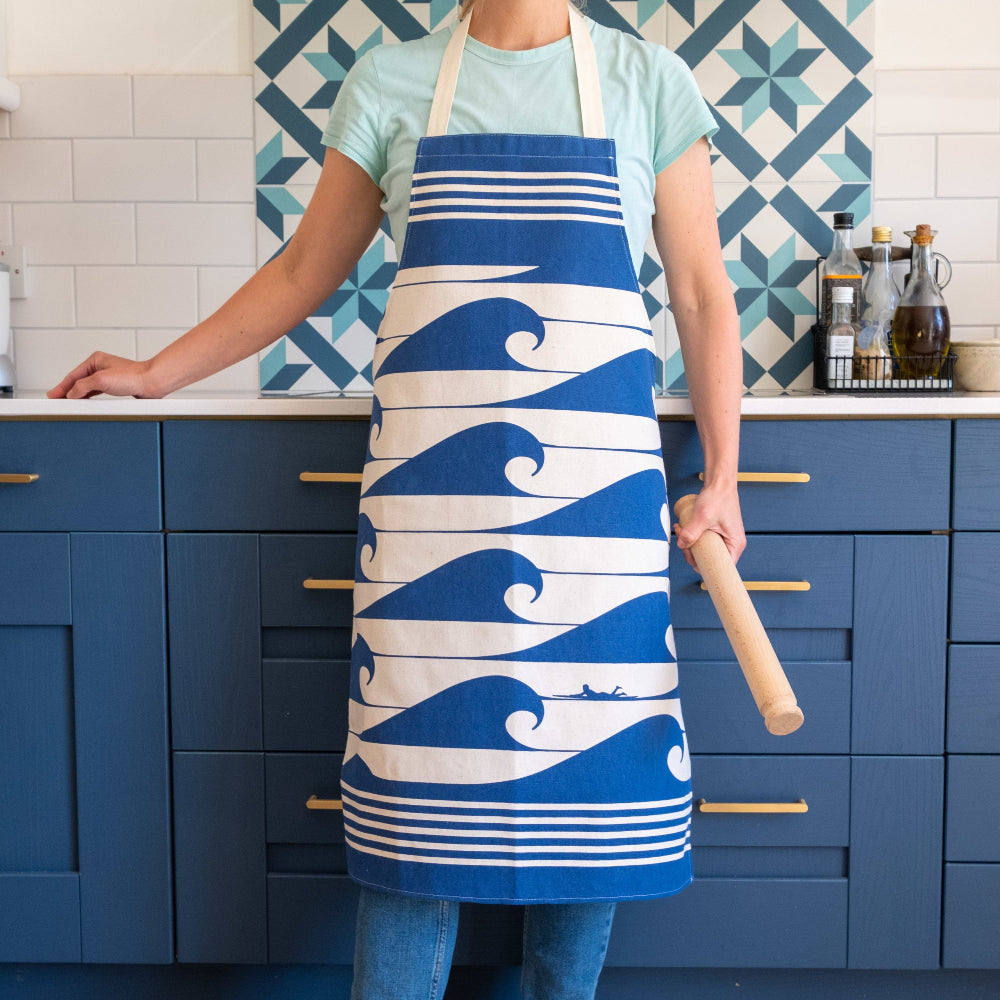 Person wearing a blue and white wave-patterned apron in a kitchen.
