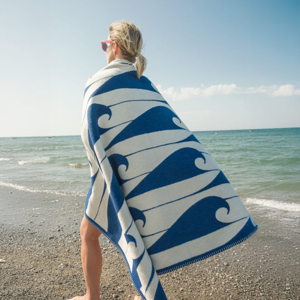 Person wrapped in a blue and white patterned towel on a beach