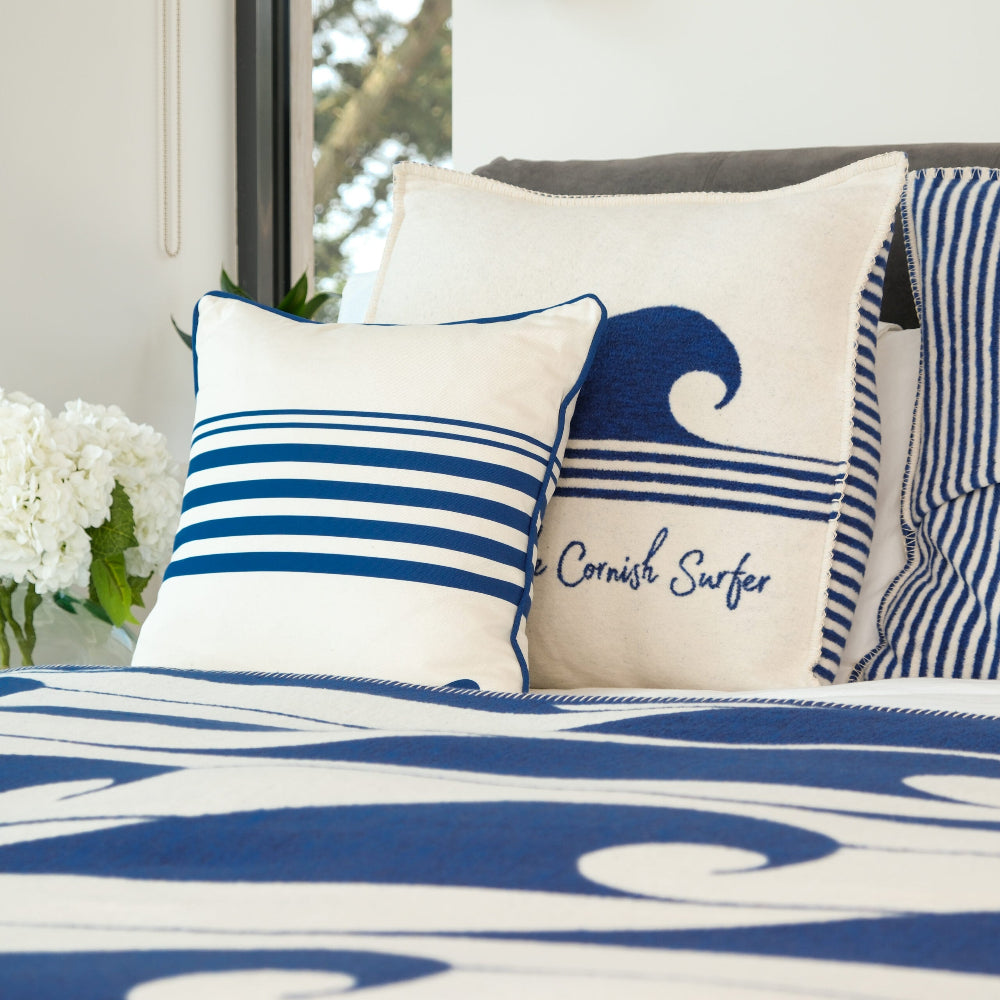 Nautical-themed pillows with wave design on a bed